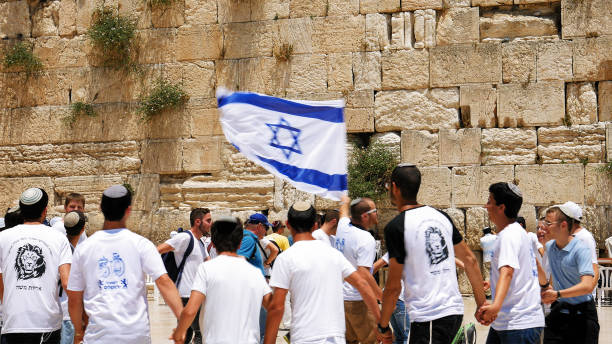 Jews dancing in a round with flag in Jerusalem Jerusalem, Israel - May 25, 2017: Jews dancing in a round with flag celebrating the Jerusalem Day at Western Wall - Wailing Wall or Kotel - the most sacred place for all jews and jewish in the world. israeli ethnicity stock pictures, royalty-free photos & images
