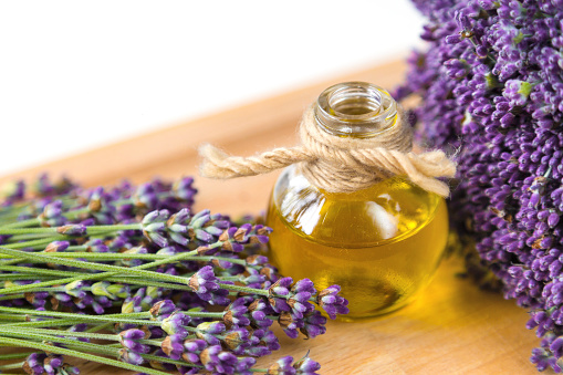 Fresh lavender flowers and bottle of oil on wooden background