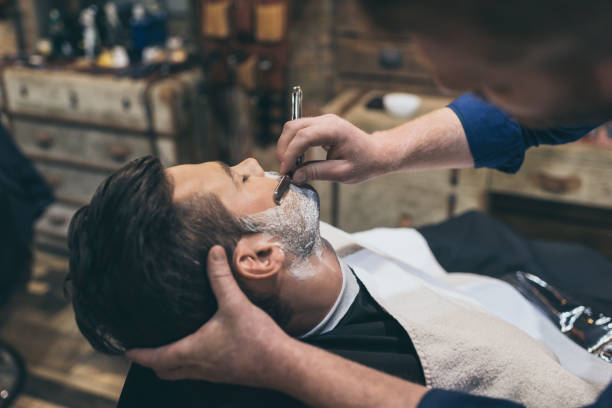 Barber shaving customer Barber shaving customers beard in vintage barber shop barber stock pictures, royalty-free photos & images