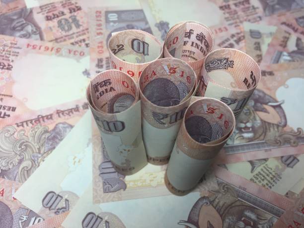 istock rolled indian ten rupees notes and coin  with 10 rupee background 826312472