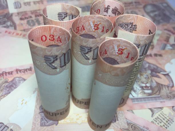 istock rolled indian ten rupees notes and coin  with 10 rupee background 826312754