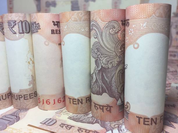 istock rolled indian ten rupees notes and coin  with 10 rupee background 826313260