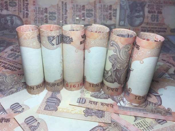istock rolled indian ten rupees notes and coin  with 10 rupee background 826315366