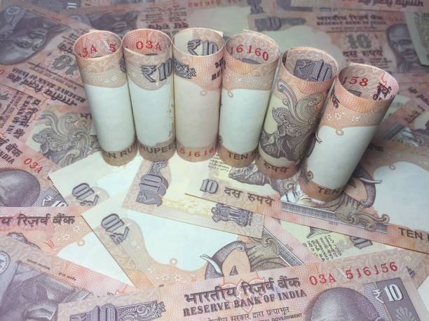 istock rolled indian ten rupees notes and coin  with 10 rupee background 826315574