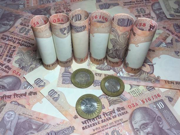 istock rolled indian ten rupees notes and coin  with 10 rupee background 826316768