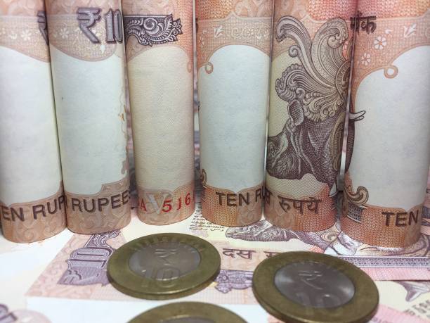 istock rolled indian ten rupees notes and coin  with 10 rupee background 826316892