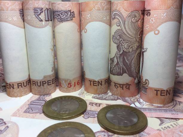 istock rolled indian ten rupees notes and coin  with 10 rupee background 826318280