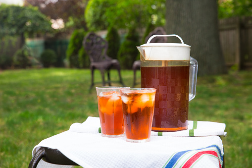Pitcher of iced tea and a glass  in outdoor backyard summer settingPitcher of iced tea and two glasses  in outdoor backyard summer setting
