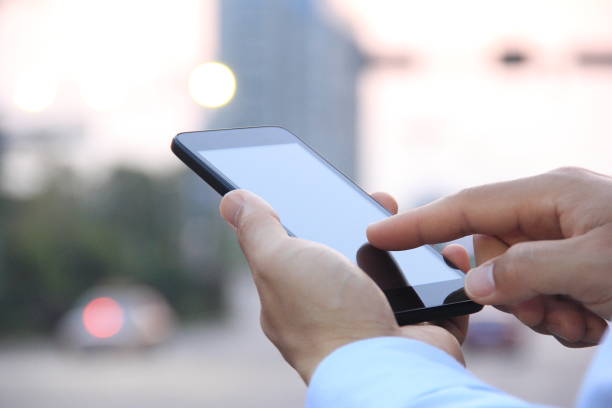 istock Male hand using smart phone on city street 826330864