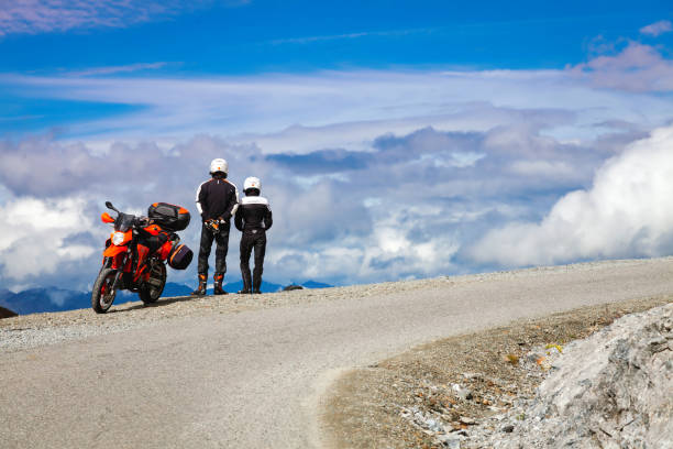 Passo dello Stelvio, Italy - July 27, 2017: a couple of young bikers with their motorcycle, looking the alps panorama, over the world famous Stelvio Pass. Photo taken in a public place.
