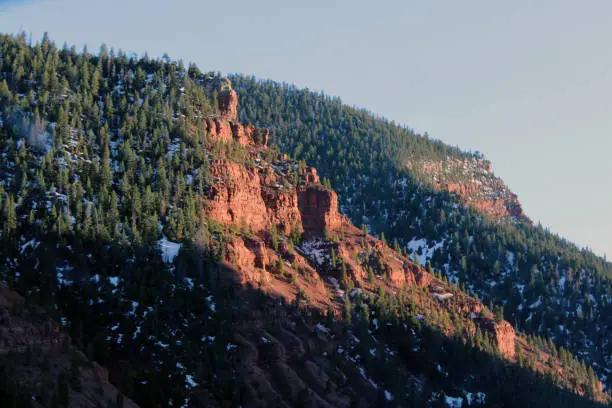 Dusk in Colorado as sun casts final light on a red rocky mountain.