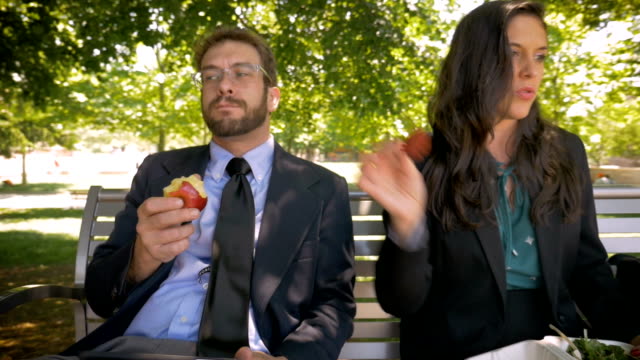 Two businesspeople dancing while sitting and eating healthy food for lunch