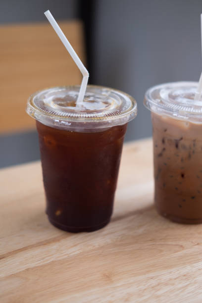 istock Plastic cup of iced black coffee americano on wood table 826359090