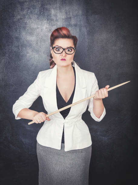 istock Serious woman teacher pointing out on blackboard background 826361942