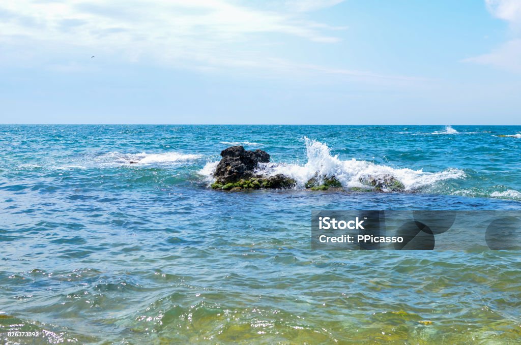 Coastal waves of the Black Sea are bumping against a protruding stone from the water. Crimea 2017 Horizontal Stock Photo