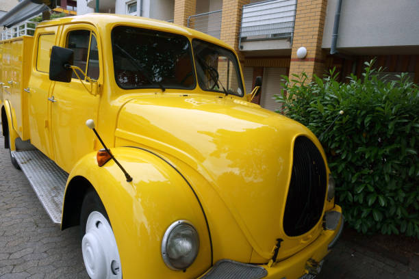 Interior of aged fire truck with steering wheel and speedometer with arrows above large leather seat in front of windshield with wipers and side mirror. Old vehicles concept