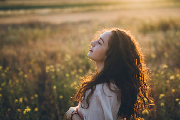 istock Beautiful young woman in a meadow in sunset 826390636