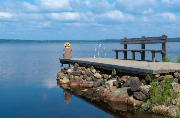 frau sitzt auf dem pier - lake tranquil scene landscape zen like stock-fotos und bilder