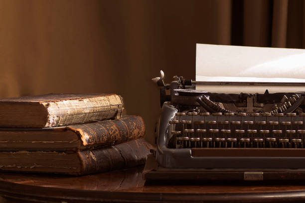 macchina da scrivere portatile vintage con un pezzo di carta e libri vintage su un tavolo - typewriter writing retro revival old fashioned foto e immagini stock