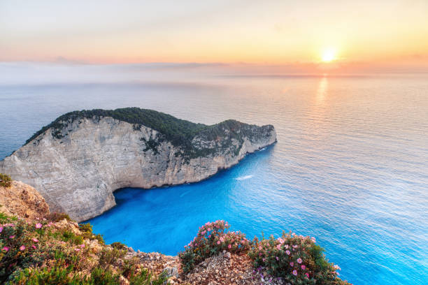 istock Sunset scenery with sun disc falling behind Ionian sea at Navagio beach with shipwreck view, Zakynthos - Zante island in Greece. Very popular and famous travel destination for summer vacations. 826419568