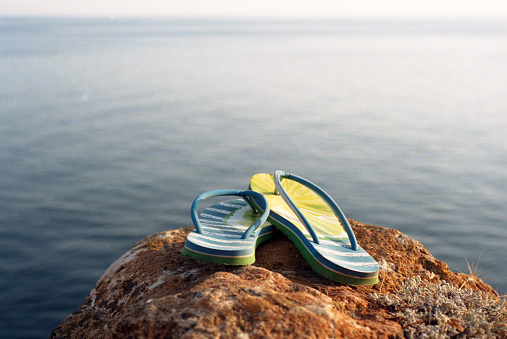 Flip-flops lying on cliff near the sea. Shot on film