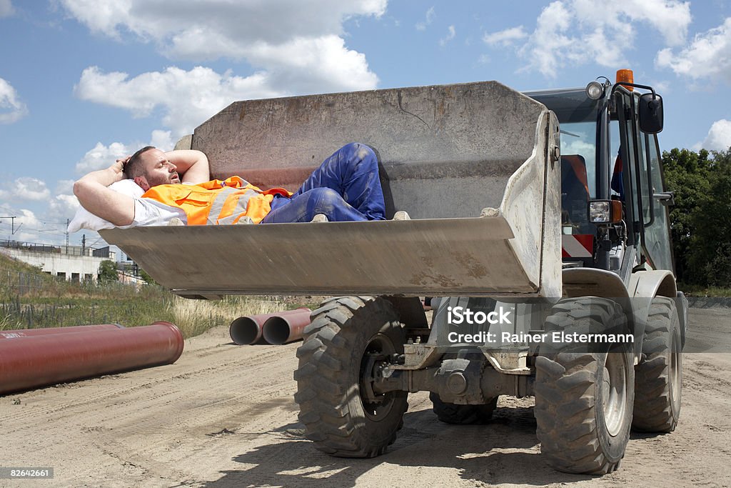 Man asleep in bucket of earth mover  Relaxation Stock Photo