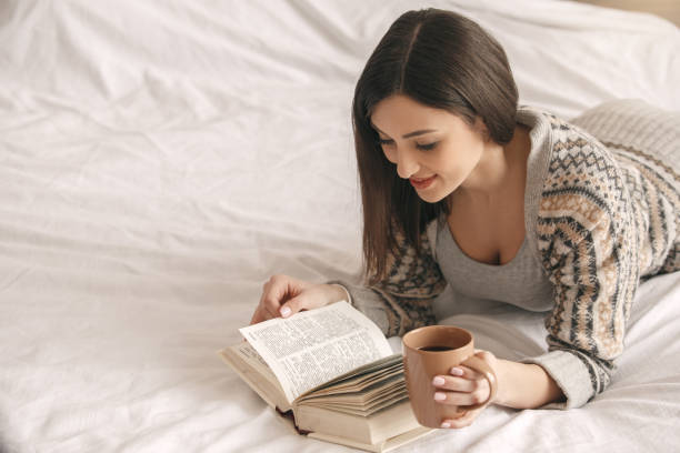 istock Young woman lie on bed with a book rest 826428446