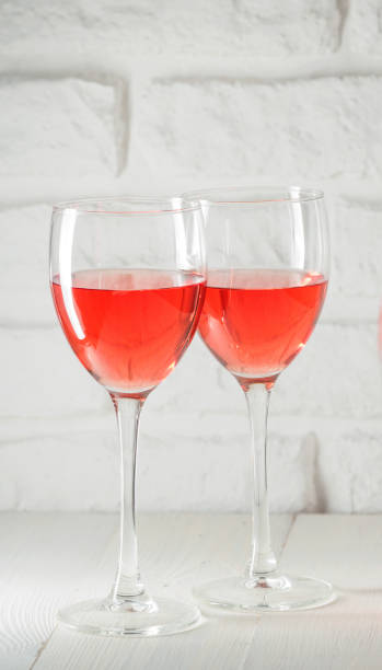 istock Two wineglass with pink wine on white brick wall background 826442638