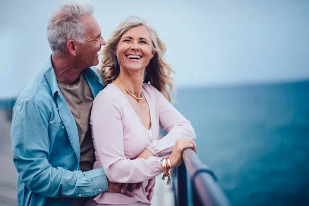 Photo of Married senior couple having fun, laughing and relaxing at seaside