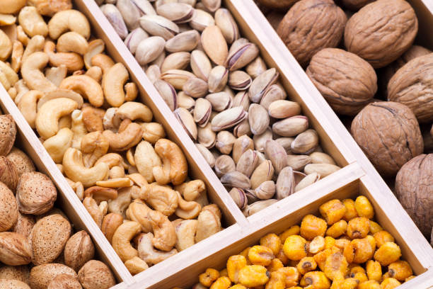 Different types of nuts in wooden box isolated on white. Walnuts, peanuts, cashew, almonds, nuts, ground nuts in bamboo wooden box.