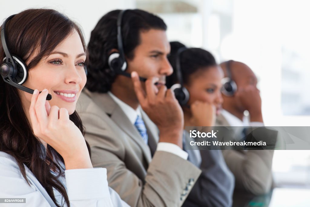 Smiling call centre employee working while accompanied by her team Young smiling call centre employee working hard and accompanied by her team 20-24 Years Stock Photo