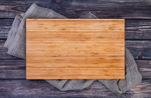 Cutting board on dark wood background, top view