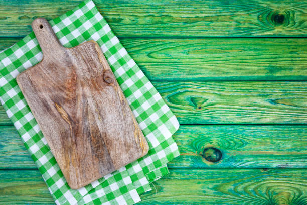 istock Cutting board over green checkered tablecloths on the table, top view 826459800