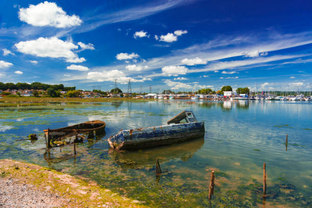 Derelict boats in the backwaters of Holes Bay, Poole Harbour at low tide