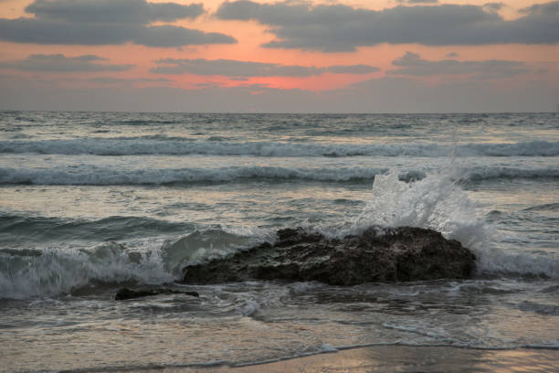 夕日の中に岩に対して砕ける波 - sailboat sunset tel aviv sea ストックフォトと画像