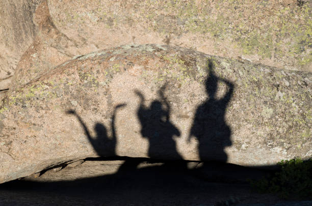 istock Shadows of happy people with arms raised on rock 826471640