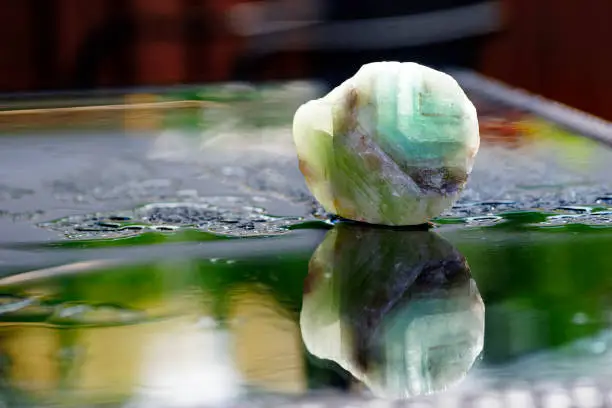 Macro green calcite mineral, reflection in the water, bokeh background