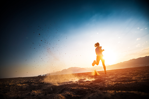 Woman runs on the desert with lots of dust