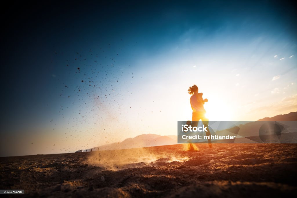 Woman runs on the desert Woman runs on the desert with lots of dust Running Stock Photo