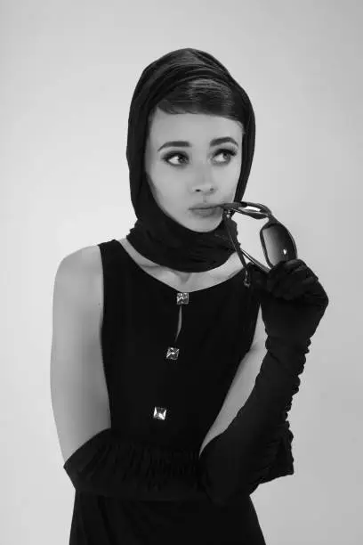 beautiful young woman in retro style with sunglasses and a head scarf black and white photography
