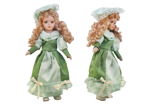 Isolated photo of old-fashioned doll in green dress with hat and curly hair on white background.