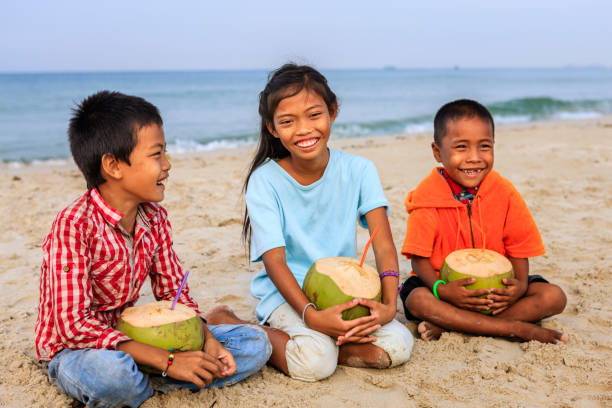istock Cambodian children holding coconuts on the beach, Cambodia 826490258