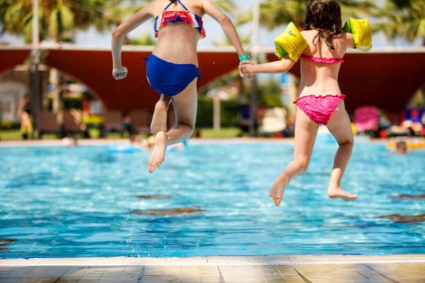 istock Two child jumping into the swimming pool 826497092