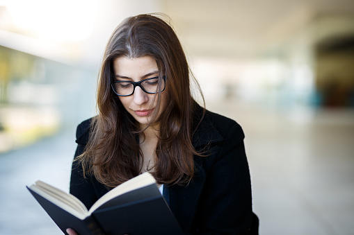 Serious girl wearing glasses reading a book