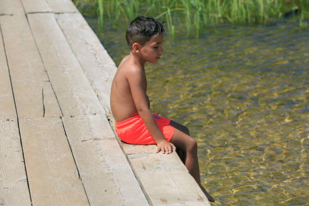 menino de estar sobre uma ponte de madeira sobre um lago - plank boardwalk pontoon bridge summer - fotografias e filmes do acervo