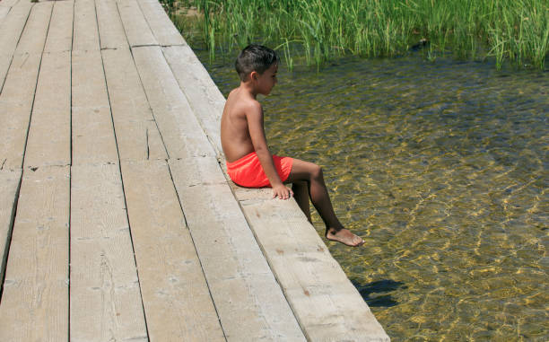 menino de estar sobre uma ponte de madeira sobre um lago - plank boardwalk pontoon bridge summer - fotografias e filmes do acervo