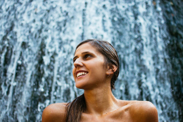istock Attractive young woman beneath the waterfall 826515780