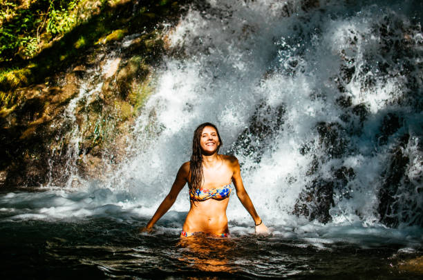 istock Attractive young woman beneath the waterfall 826516094