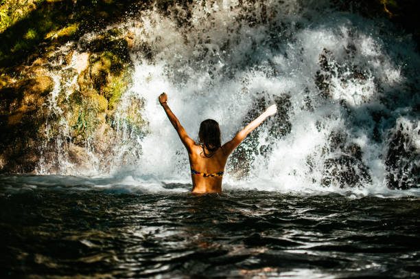 istock Attractive young woman beneath the waterfall 826516190
