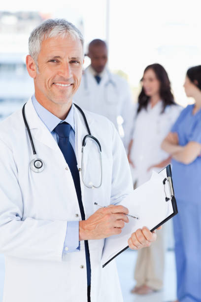 istock Mature doctor showing a beaming smile while pointing to something on his clipboard 826518662
